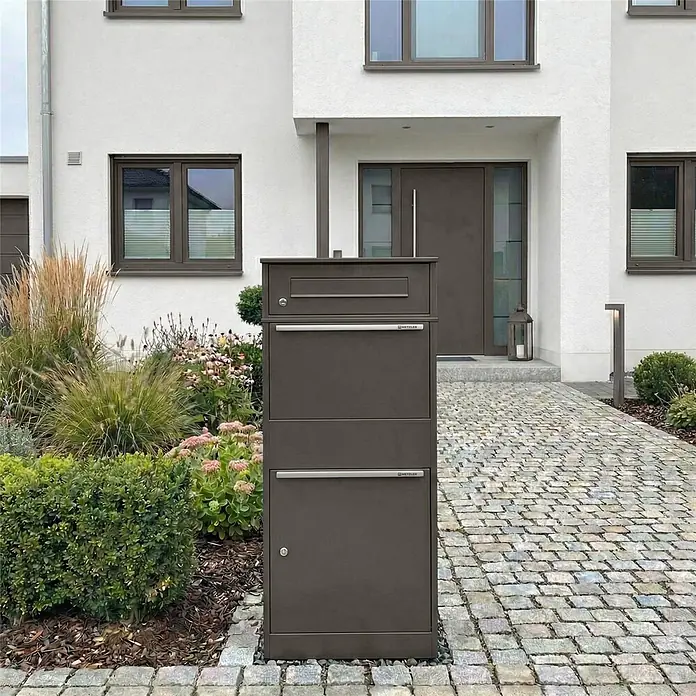 Metzler Paketbox BRFK BISPO - L x B x H: 37,4 x 50,3 x 112,9 cm, Eisenglimmer, Stahl, Paketfach - Freistehende dunkelbraune Metall-Paketbox mit integriertem Briefkasten vor einem modernen Haus.