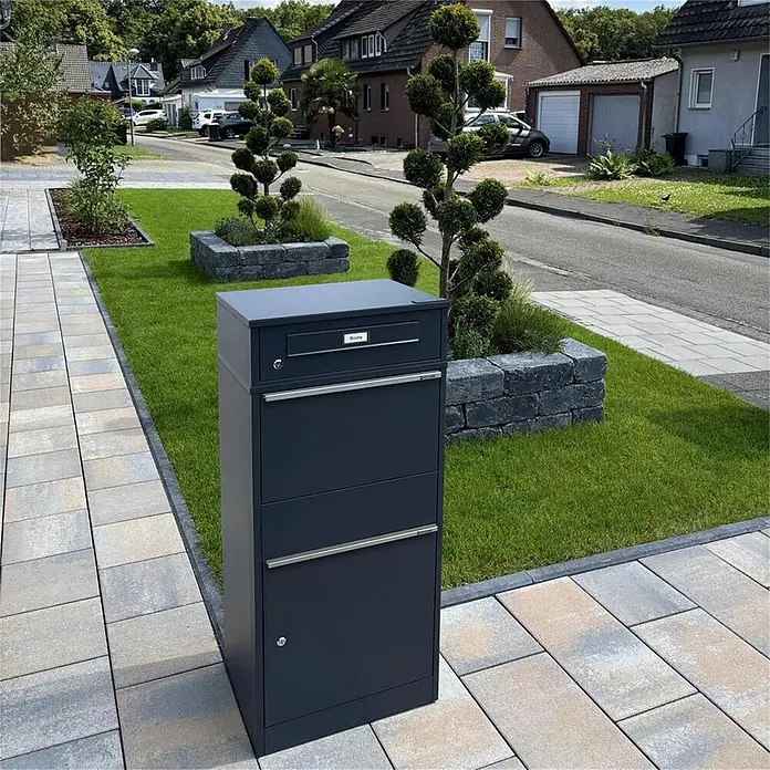 Metzler Paketbox BRFK BISPO RE - L x B x H: 37,4 x 50,3 x 112,9 cm, Anthrazit, Stahl, Paketfach - Dunkelgrauer Standbriefkasten auf gepflastertem Weg in einem Wohngebiet.