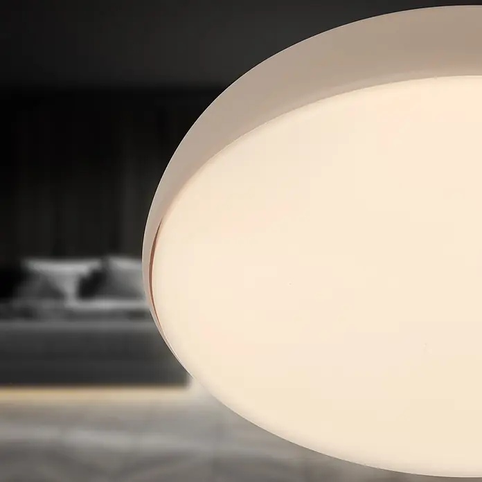 Brilo Plafón LED redondo Nikan - 20 W, Ø x Al: 35 x 8,5 cm, Beige, Blanco neutro - Lámpara LED redonda blanca que emite un brillo suave, vista sobre un fondo de dormitorio difuminado.