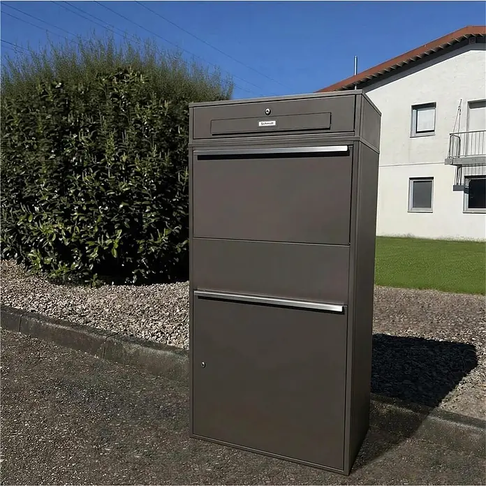 Metzler Paketbox XL BRFK MAX RE - L x B x H: 45,4 x 72 x 145 cm, Eisenglimmer, Stahl, Paketfach - Dunkelgrauer Schmidt Paketbriefkasten mit integriertem Lieferfach, im Freien aufgestellt.