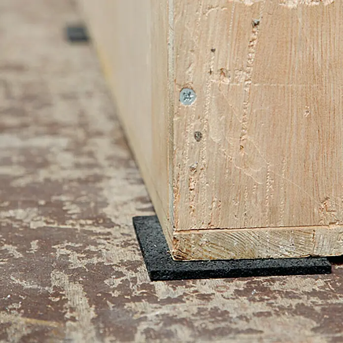 Conacord Antirutschmatte - 100 x 100 mm, Temperaturbereich: -40 °C - 115 °C - Holzbein auf einer schwarzen, quadratischen Gummiauflage, die das Holz vor Kratzern schützt und für Stabilität sorgt. Perfekt für Möbel!