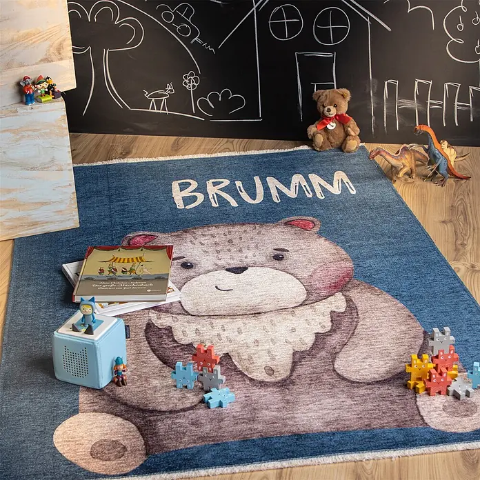 Kayoom Kinderteppich Joanna 623 - Multi, 170 x 115 cm, 70 % Baumwolle, 30 % Polyester - Blauer Kinderteppich mit großem braunen Bären und 'BRUMM'-Schriftzug, in einem Spielzimmer mit Spielzeug.