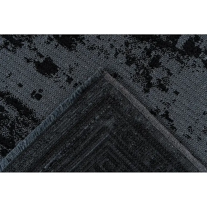 Kayoom Flachgewebeteppich Kalea 325 - Schwarz, 170 x 120 cm, 100 % Polyester - Dunkelgrauer Teppich mit abstrakten schwarzen Mustern, gefaltet, um die Webart und den Saum der Rückseite zu zeigen.