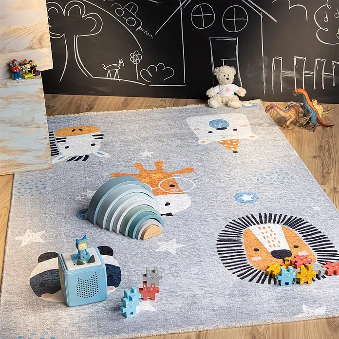 Kayoom Kinderteppich Joanna 613 - Multi, 170 x 115 cm, 70 % Baumwolle, 30 % Polyester - Grauer Kinderteppich mit Comic-Tiergesichtern und Sternen, darauf Spielzeug wie Regenbogen-Stapler und Bausteine im Spielbereich.