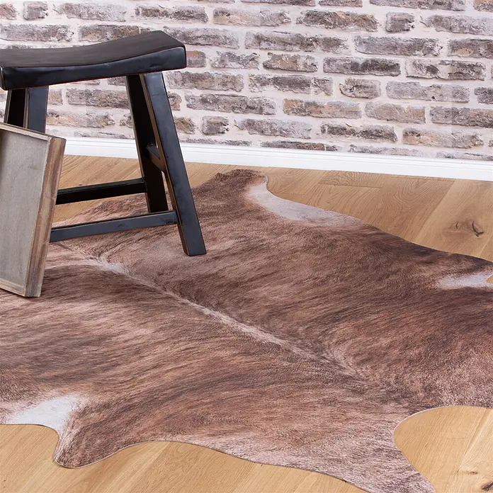 Kayoom Kunstfell Sanari 204 - Braun, 190 x 155 cm, 100 % Polyester - Faux-Kuhfellteppich mit braunem Tigerstreifenmuster auf Holzboden, teilweise unter einem schwarzen Hocker.