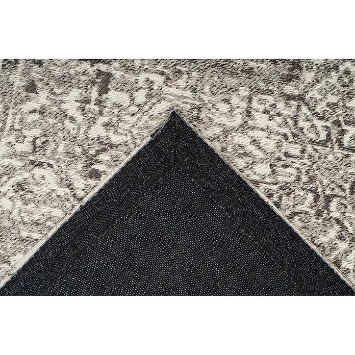 Kayoom Kurzflorteppich Davis 225 - Grau, 230 x 160 cm, 100 % Polyester - Nahaufnahme eines hellen Teppichs mit dunklem Muster, Ecke umgeklappt, um die schwarze Rückseite zu zeigen.