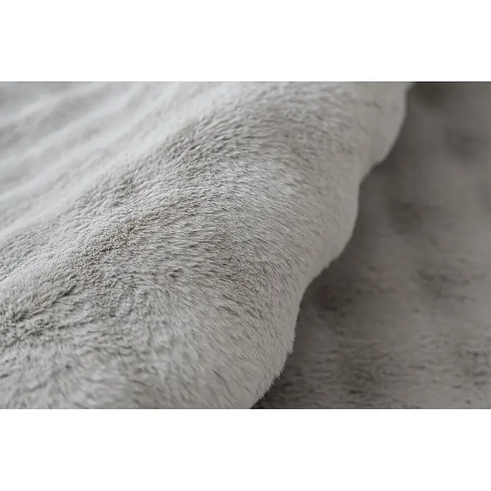 Kayoom Fellteppich Hailey 125 - Grau, 120 x 160 cm, 100 % Polyester - Nahaufnahme von weichem, plüschigem grauem Kunstfellstoff mit einer sanften Falte, die seine luxuriöse Textur hervorhebt.