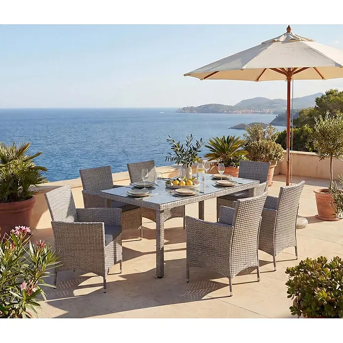 Mendler Gartenmöbel-Set - 7 -tlg., Polyrattan, Grau, Kissen anthrazit, Grau, Kissen anthrazit - Graues Rattan-Gartenessgruppe mit Glastisch und sechs Stühlen, auf sonniger Terrasse mit Meerblick.