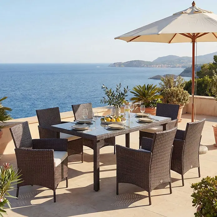 Mendler Poly-Rattan-Garnitur Halden - braun, Kissen Creme -  - Braunes Polyrattan-Gartenset mit Glastisch und Stühlen auf einer Terrasse mit Meerblick.