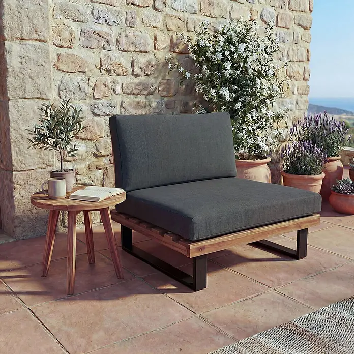Mendler Garten-Loungesessel HWC-H54 - 1 Stk., Holz, Braun, Polster dunkelgrau, B x T x H: 82 x 82 x 75 cm - Garten-Sessel mit dunkelgrauen Kissen, Holzrahmen und schwarzen Metallbeinen, auf einer Terrasse neben einem Beistelltisch.