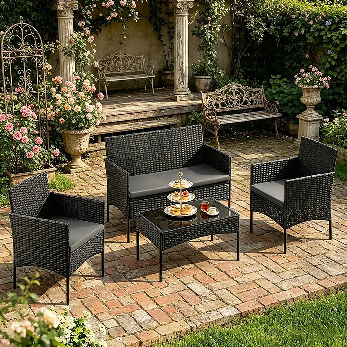 SONNENH Loungemöbel-Set 4-teilig für 4 Personen Schwarz -  - Eine 4-teilige schwarze Rattan-Gartenmöbelgruppe mit grauen Kissen auf einer Ziegelterrasse. Besteht aus Sofa, zwei Stühlen und Couchtisch.