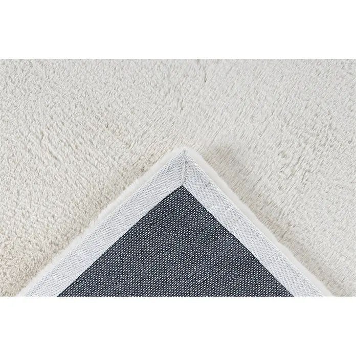Kayoom Fellteppich Emotion 525 - Creme, 110 x 60 cm, 100 % Polyester - Weißer flauschiger Teppich, dessen Ecke umgeklappt ist, um die dunkelgraue Rückseite mit hellem Rand zu zeigen.