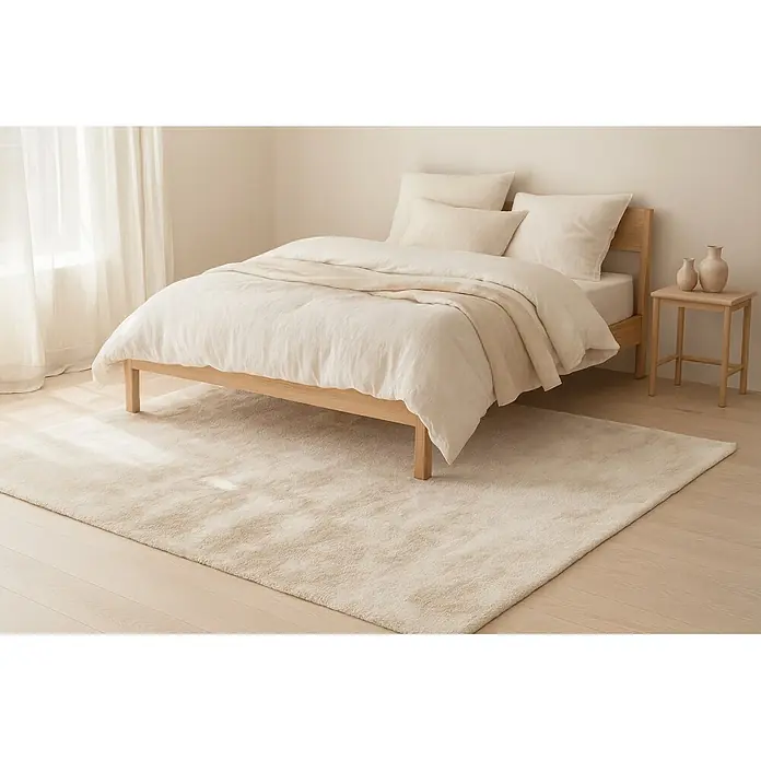 Kayoom Fellteppich Emotion 525 - Creme, 110 x 60 cm, 100 % Polyester - Minimalistisches Schlafzimmer mit hellem Holzbett, naturweißer Leinenbettwäsche und cremefarbenem Teppich.