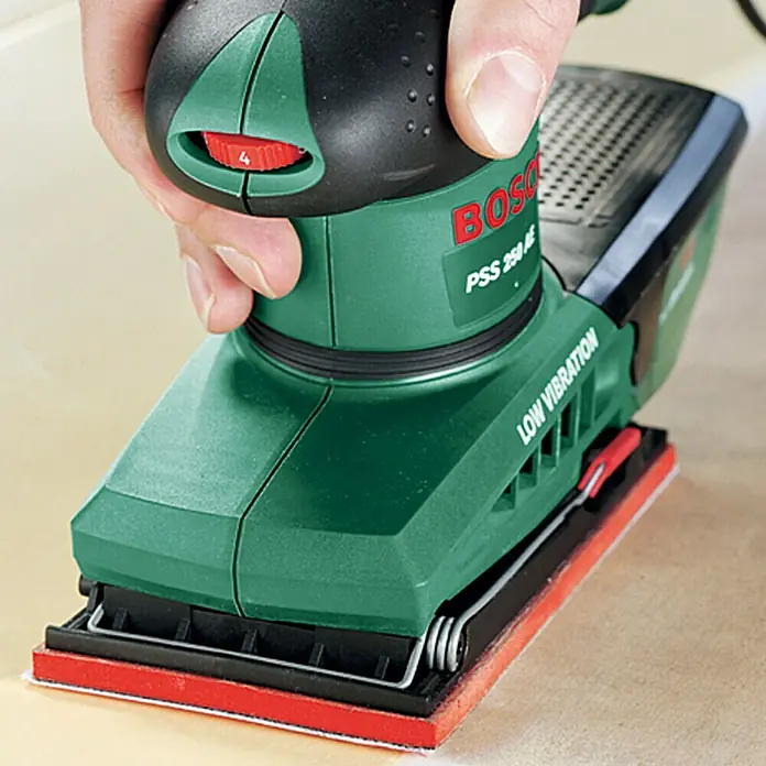 Bosch Elektro-Schwingschleifer PSS 250 AE - 250 W, Leerlaufschwingzahl: 14.000 U/min - 24.000 U/min - Nahaufnahme eines Bosch PSS 250 AE Schwingschleifers in Aktion, gehalten von einer Hand. Das Gerät verfügt über eine variable Geschwindigkeitsregelung.
