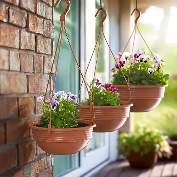 Plastard Blumenampel 3er Set Ø 25 cm in Terrakotta mit Aufhänger, Deko Blumentopf - 3 Stk., Außenmaß (Ø x H): 25 x 10 cm, Kunststoff, Terrakotta - Drei braune Kunststoff-Hängekörbe mit bunten Blumen, draußen an einer Veranda neben einer Ziegelwand aufgehängt.