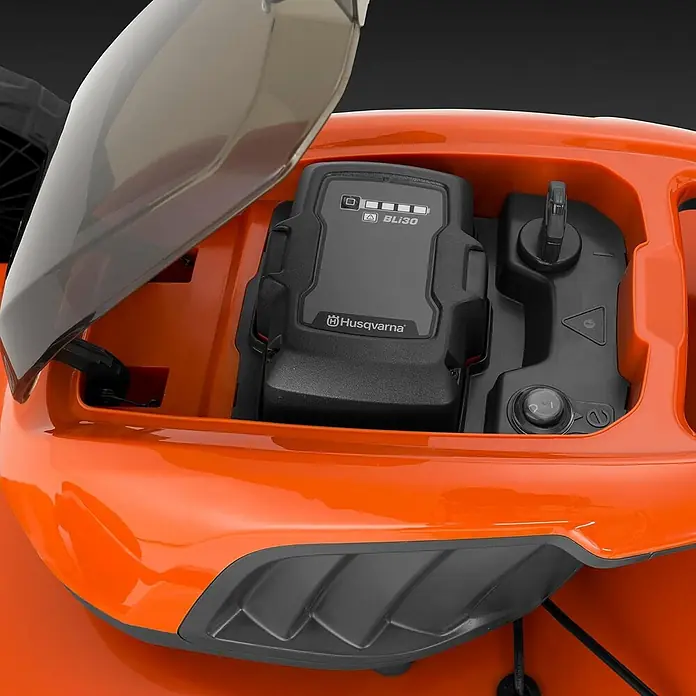 Husqvarna LC 142i Akku-Rasenmäher 42 cm 36V klappbar ohne Akku -  - Offenes Fach eines orangefarbenen Geräts, zeigt eine Husqvarna BLi30 Batterie und ein Bedienfeld.