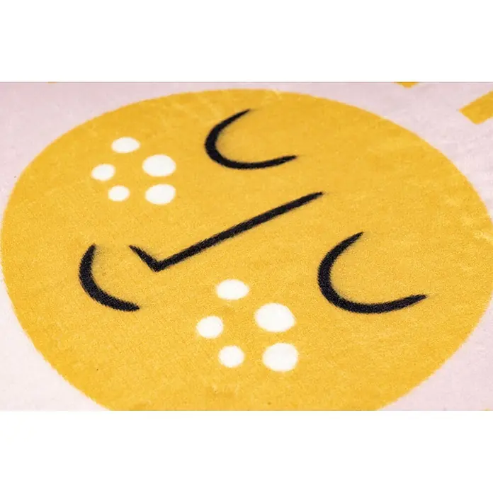 Kayoom Kinderteppich Wonder 126 - Rosa, 160 x 115 cm, 100 % Polyester - Nahaufnahme von weichem gelbem Stoff mit fröhlichem Gesicht, schwarzen Linien und weißen Punkten auf rosa Hintergrund.