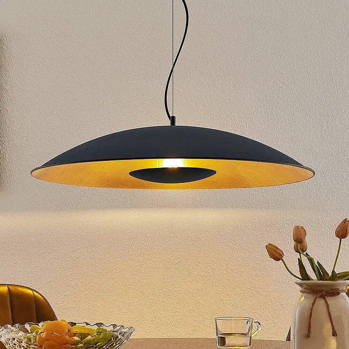 Lindby Pendelleuchte Narisara - schwarz, Schwarz, gold, E27 - Schwarze und goldene scheibenförmige Pendelleuchte, die einen Esstisch mit warmem Licht beleuchtet.