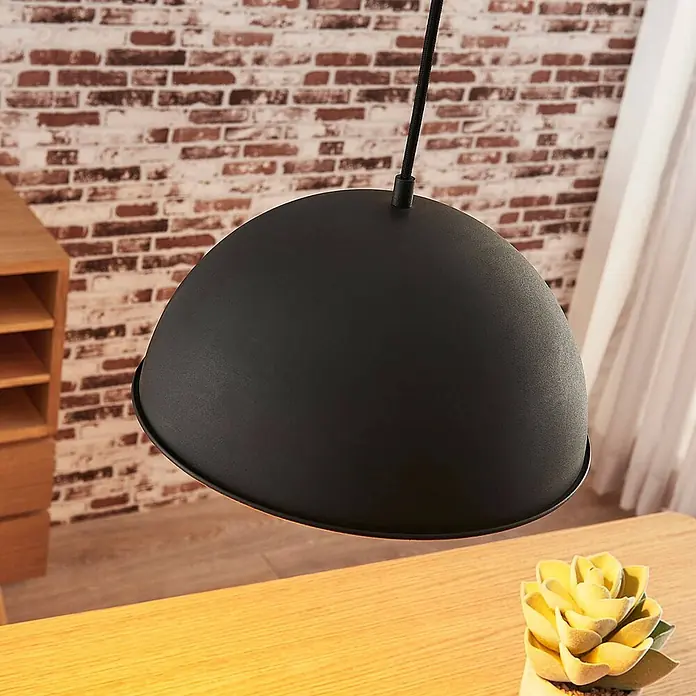 Lindby Pendelleuchte Leya - schwarz, Schwarz, gold, E27 - Schwarze, kuppelförmige Pendelleuchte hängt über einem Holztisch.