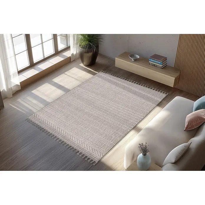 Kayoom Fransenteppich Reef 125 - Silber, 150 x 80 cm, 100 % Polypropylen - Beiger Teppich mit Fransen auf hellem Holzboden in einem gemütlichen Wohnzimmer.