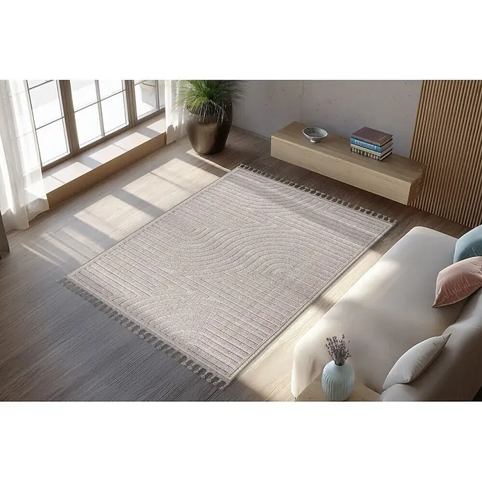 Kayoom Fransenteppich Reef 225 - Silber, 150 x 80 cm, 100 % Polypropylen - Heller beigefarbener Webteppich mit geometrischen und wellenförmigen Mustern, auf hellem Holzboden in einem modernen Wohnzimmer.
