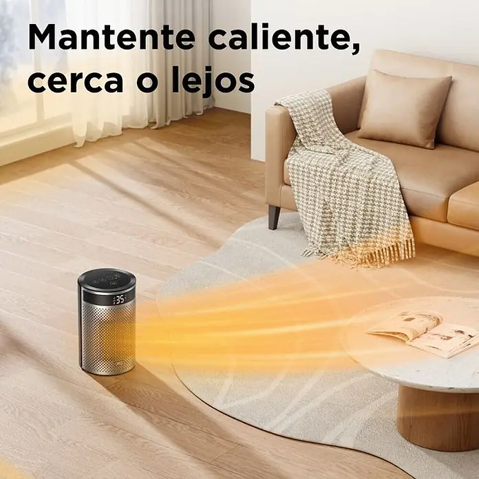 Dreo Calefactor cerámico portátil Atom - 900 kW - 1.500 kW, Negro/Plata, Fijo, 10 m² - 20 m² - Calefactor cilíndrico plateado y negro con pantalla digital, emitiendo aire cálido por el suelo de un salón hacia un sofá.