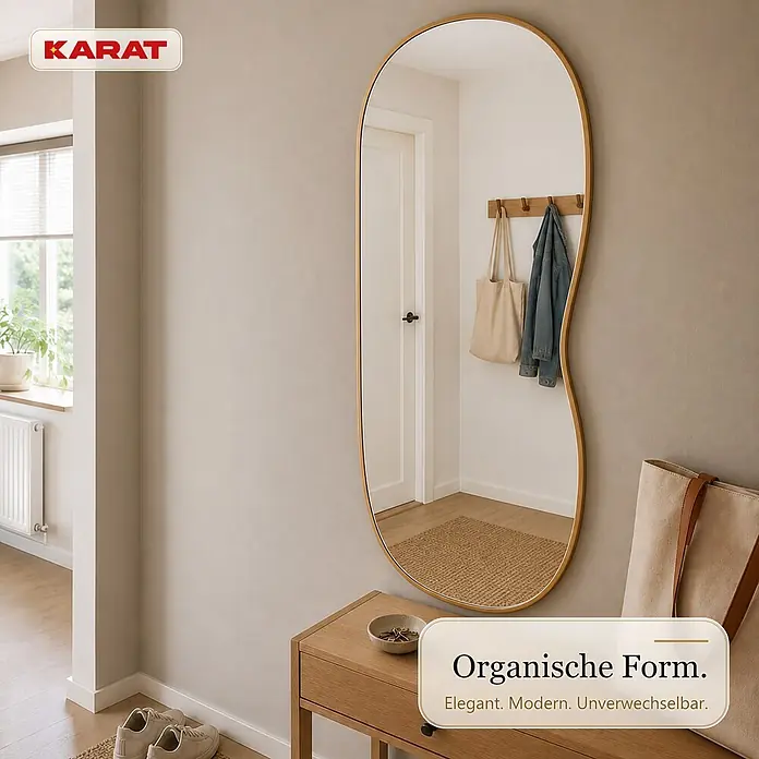 Floordirekt Wandspiegel Serena - 60,1 x 120,1 cm - Ganzkörperspiegel mit goldenem Rahmen und organischer Form im Flur über einer Holzkonsole, der eine Garderobe reflektiert.