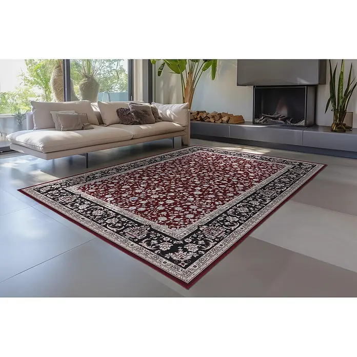 Kayoom Kurzflorteppich Rocks 125 - Rot, 290 x 200 cm, 100 % Polyester - Rot-schwarz-weiß gemusterter Teppich mit Blumenmuster in einem modernen Wohnzimmer unter einem Sofa.