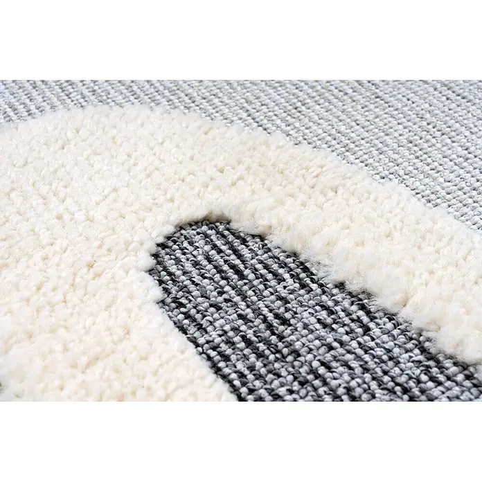 Kayoom Kinderteppich Modena 420 - Grau, 170 x 120 cm, 100 % Polypropylen - Nahaufnahme eines Teppichs mit flauschigen cremefarbenen Hochflor- und gewebten grau-schwarzen Niedrigflorpartien.