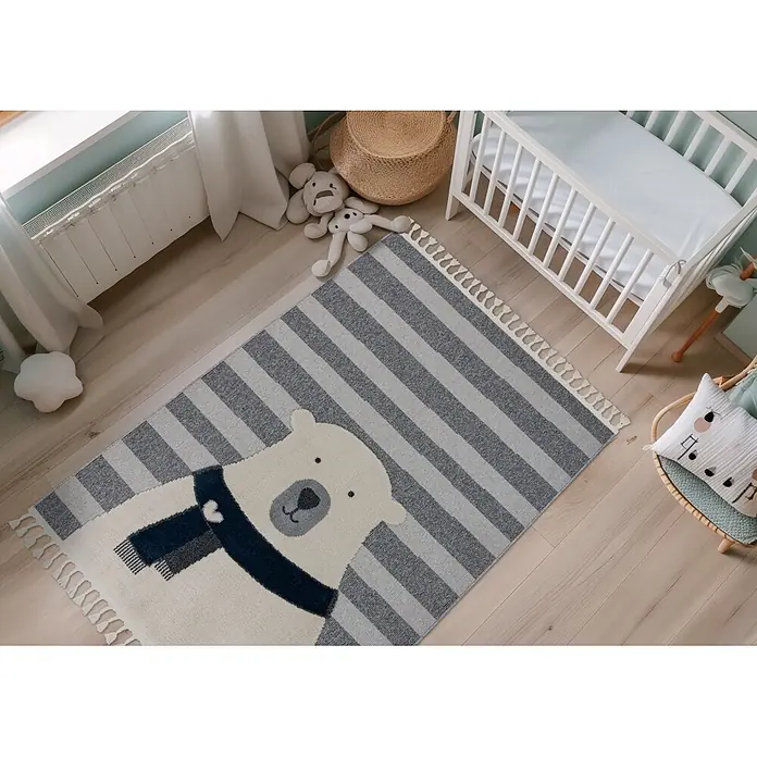 Kayoom Kinderteppich Modena 423 - Grau, 170 x 120 cm, 100 % Polypropylen - Ein gestreifter Teppich in Hellgrau und Dunkelgrau mit einem großen weißen Eisbären, der einen blauen Schal trägt, auf Holzboden im Kinderzimmer.