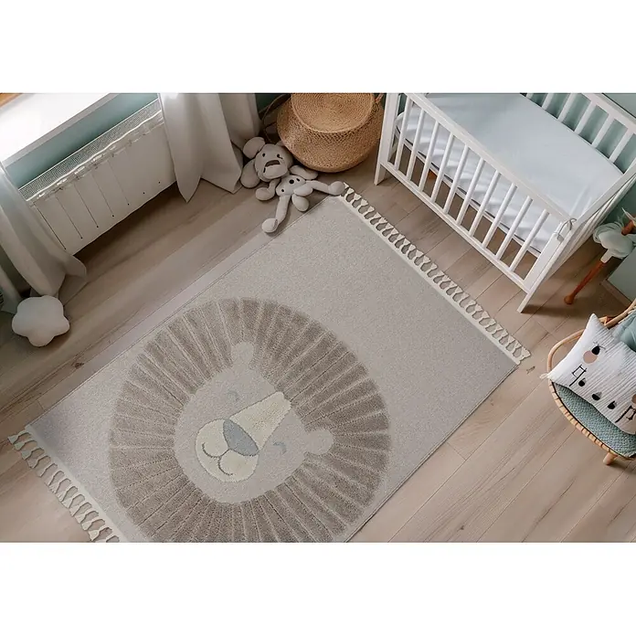 Kayoom Kinderteppich Modena 424 - Grau, 170 x 120 cm, 100 % Polypropylen - Ein beiger Kinderteppich mit hellbraunem Löwenmotiv und Quasten, auf einem Holzfußboden in einem Kinderzimmer.