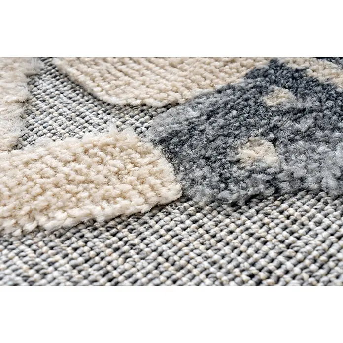 Kayoom Kinderteppich Modena 418 - Grau, Durchmesser: 133 cm, 100 % Polypropylen - Nahaufnahme eines strukturierten Teppichs mit cremefarbenem Hochflor und grauen Webbereichen.