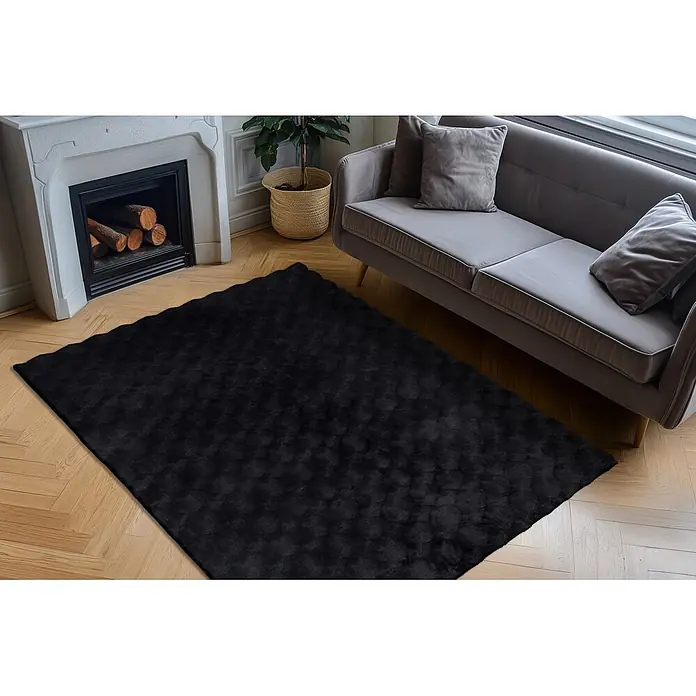 Kayoom Fellteppich Royal Glow 825 - Anthrazit, 290 x 200 cm, 80 % Polyester, 20 % Baumwolle - Schwarzer flauschiger Teppich unter einem grauen Sofa und nahe einem weißen Kamin im Wohnzimmer.