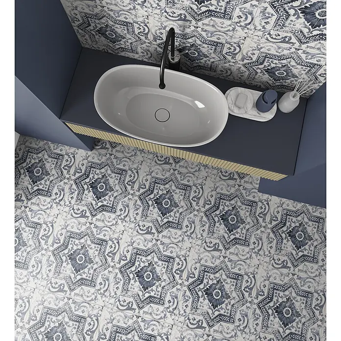 Halcón Pavimento porcelánico Kilkenny - 45 x 45 cm, Azul y blanco, Mate - Vista superior de un tocador de baño con lavabo ovalado blanco, grifo negro y encimera azul oscuro. Paredes y suelo cubiertos con azulejos estampados azules y blancos.