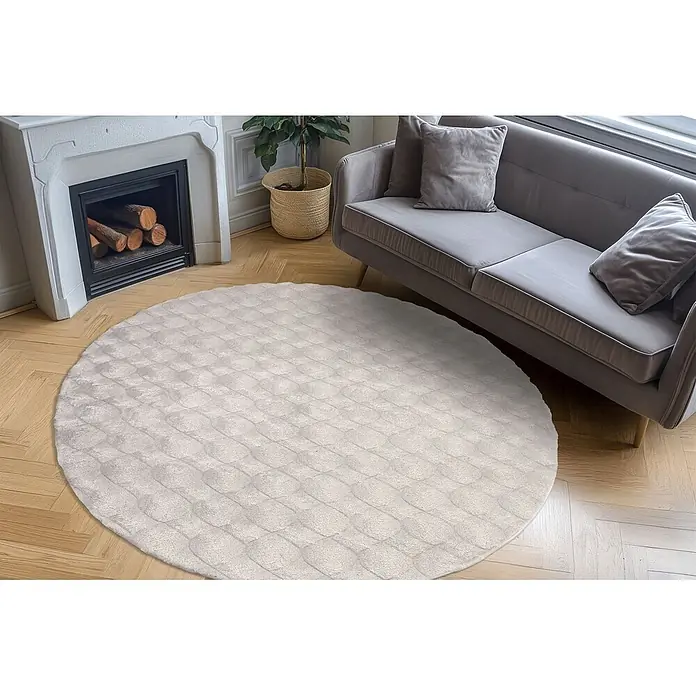 Kayoom Fellteppich Royal Glow 825 - Grau, Durchmesser: 200 cm, 80 % Polyester, 20 % Baumwolle - Runder, hellgrauer Teppich mit subtilem Texturmuster auf Holzboden in einem Wohnzimmer.