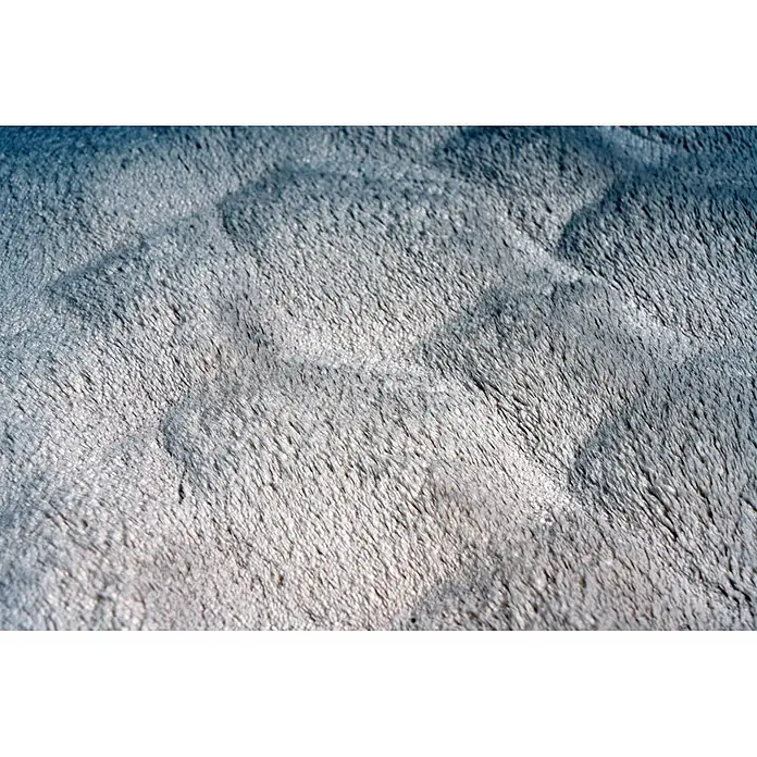Kayoom Fellteppich Royal Glow 825 - Creme, Durchmesser: 200 cm, 80 % Polyester, 20 % Baumwolle - Nahaufnahme eines weichen, plüschigen Stoffes in Weiß und Blau-Grau mit gewellter, strukturierter Oberfläche.