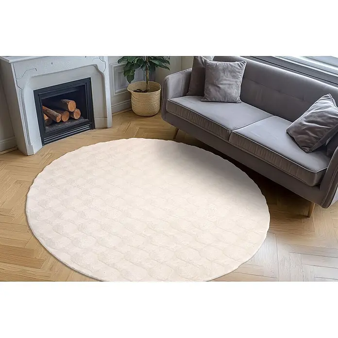 Kayoom Fellteppich Royal Glow 825 - Creme, Durchmesser: 200 cm, 80 % Polyester, 20 % Baumwolle - Heller, runder, strukturierter Teppich auf Holzboden, ergänzt ein graues Sofa im Wohnzimmer.