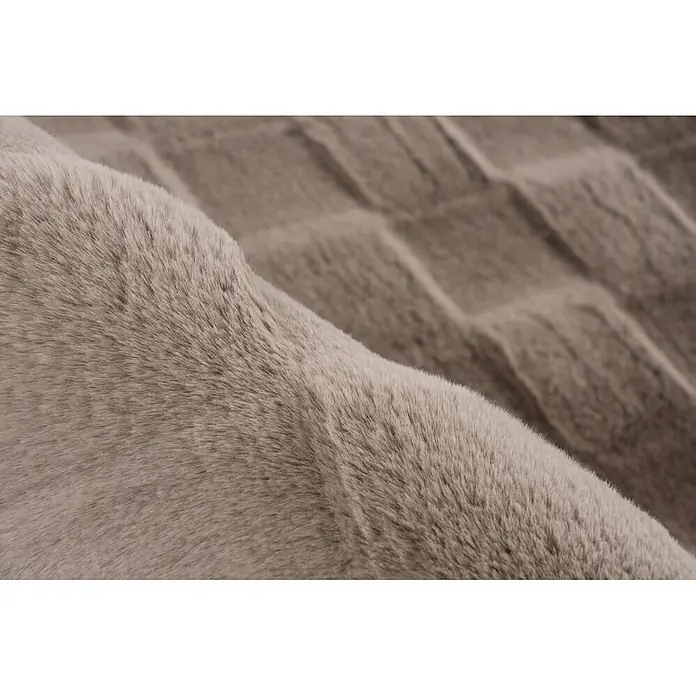 Kayoom Hochflorteppich Botany 625 - Taupe, 150 x 80 cm, 100 % Polyester - Weicher, plüschiger beiger Kunstpelzstoff, gefaltet, um seine reiche Textur und Tiefe zu zeigen.