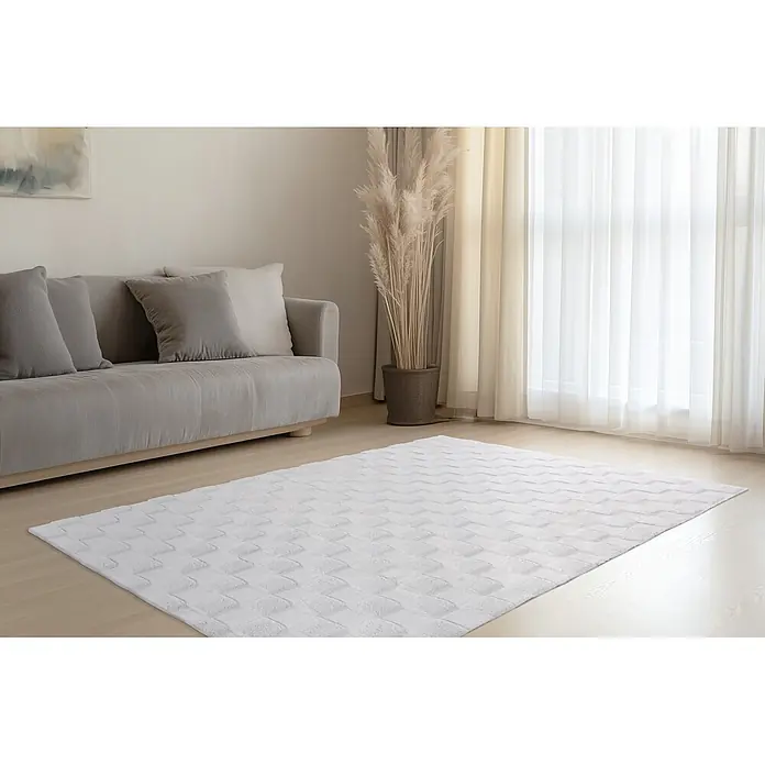 Kayoom Hochflorteppich Botany 625 - Silber, 150 x 80 cm, 100 % Polyester - Weißer Teppich mit geometrischem Muster auf hellem Holzboden in gemütlichem Wohnzimmer.