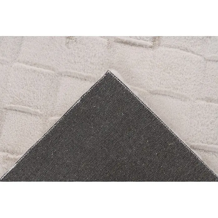 Kayoom Hochflorteppich Botany 625 - Helltaupe, 230 x 160 cm, 100 % Polyester - Hellgrauer flauschiger Teppich mit angehobener Ecke, die die dunkelgraue rutschfeste Unterseite zeigt.