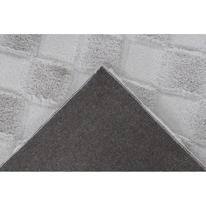 Kayoom Hochflorteppich Botany 625 - Silber, 150 x 80 cm, 100 % Polyester - Hellgrauer flauschiger Teppich, gefaltet, um seine dunkelgraue Antirutsch-Unterseite zu zeigen.
