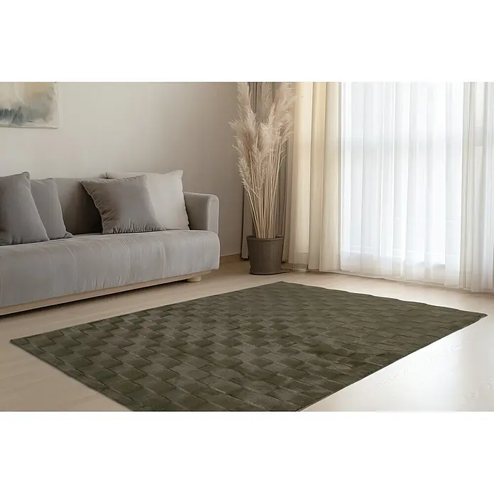 Kayoom Hochflorteppich Botany 625 - Grün, 150 x 80 cm, 100 % Polyester - Dunkelolivgrüner strukturierter Teppich auf hellem Holzboden im Wohnzimmer unter einem grauen Sofa.