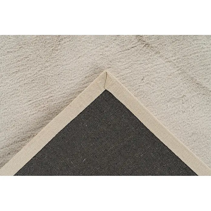 Kayoom Fellteppich Cross 425 - Creme, 230 x 160 cm, 100 % Polyester - Hellbeiger Plüschteppich mit angehobener Ecke, die seine dunkelgraue Webunterseite und beige Kante zeigt.
