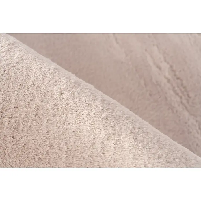 Kayoom Fellteppich Cross 425 - Pastellrosa, Durchmesser: 160 cm, 100 % Polyester - Weiches beiges Kunstfellgewebe, das seine flauschige Textur und eine leichte Faltung zeigt.