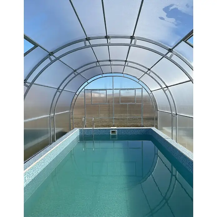 Garten Dream Poolüberdachung Grand Oasis, 4mm Polycarbonat - L x B x H: 800 x 400 x 289 cm - Gewölbte transparente Polycarbonat-Poolüberdachung mit grauem Metallrahmen über einem hellblauen Fliesenpool.