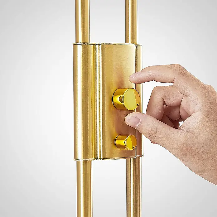 Lindby LED-Deckenfluter Seppa - messing / gold, messing / gold, Warmweiß - Nahaufnahme einer Hand, die zwei goldene Bedienknöpfe an einem gebürsteten Goldpanel eines Geräts einstellt.