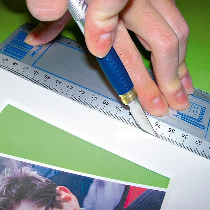 Wisent Präzisionsmesser PM 7 - 7 -tlg. - Nahaufnahme einer Hand, die mit einem Bastelmesser und einem Lineal ein Stück Papier schneidet.