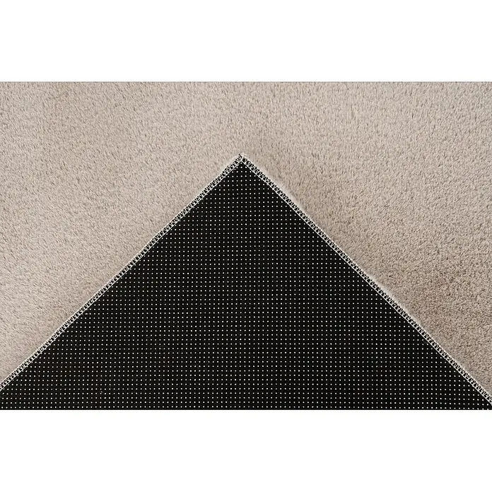 Kayoom Fellteppich Emperor 525 - Helltaupe, 290 x 200 cm, 100 % Polyester - Helles beiges, flauschiges Teppichstück mit umgeklappter Ecke, die die schwarze, rutschfeste Unterseite mit Punkten zeigt.