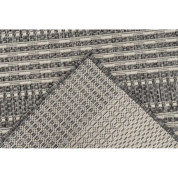 Kayoom Outdoor-Teppich Nibru 125 - Silber, 290 x 200 cm, 100 % Polypropylen - Nahaufnahme eines grau-weiß gemusterten Teppichs, dessen Ecke umgeschlagen ist, um die gewebte Rückseite zu zeigen.