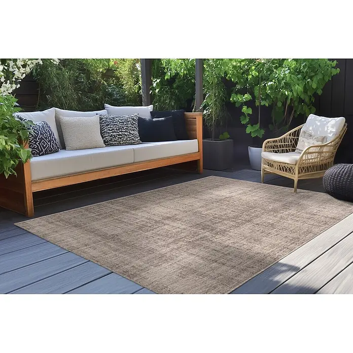 Kayoom Outdoor-Teppich Nibru 625 - Taupe, 290 x 200 cm, 100 % Polypropylen - Ein rechteckiger, hellbeiger Outdoorteppich mit dezentem Used-Muster, auf einer grauen Terrasse in einem Außenbereich.